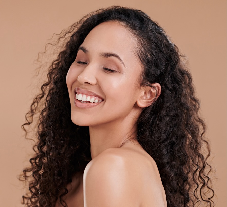 Shot of a beautiful young woman laughing and posing against a brown background