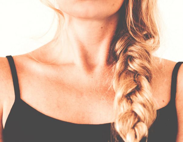 Blonde woman with braided hair on a white background for the hair restoration PRP blog.